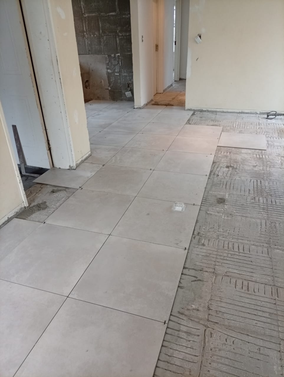 Floor tiling laid through a bedroom passage, boxes of tiles stacked and ready