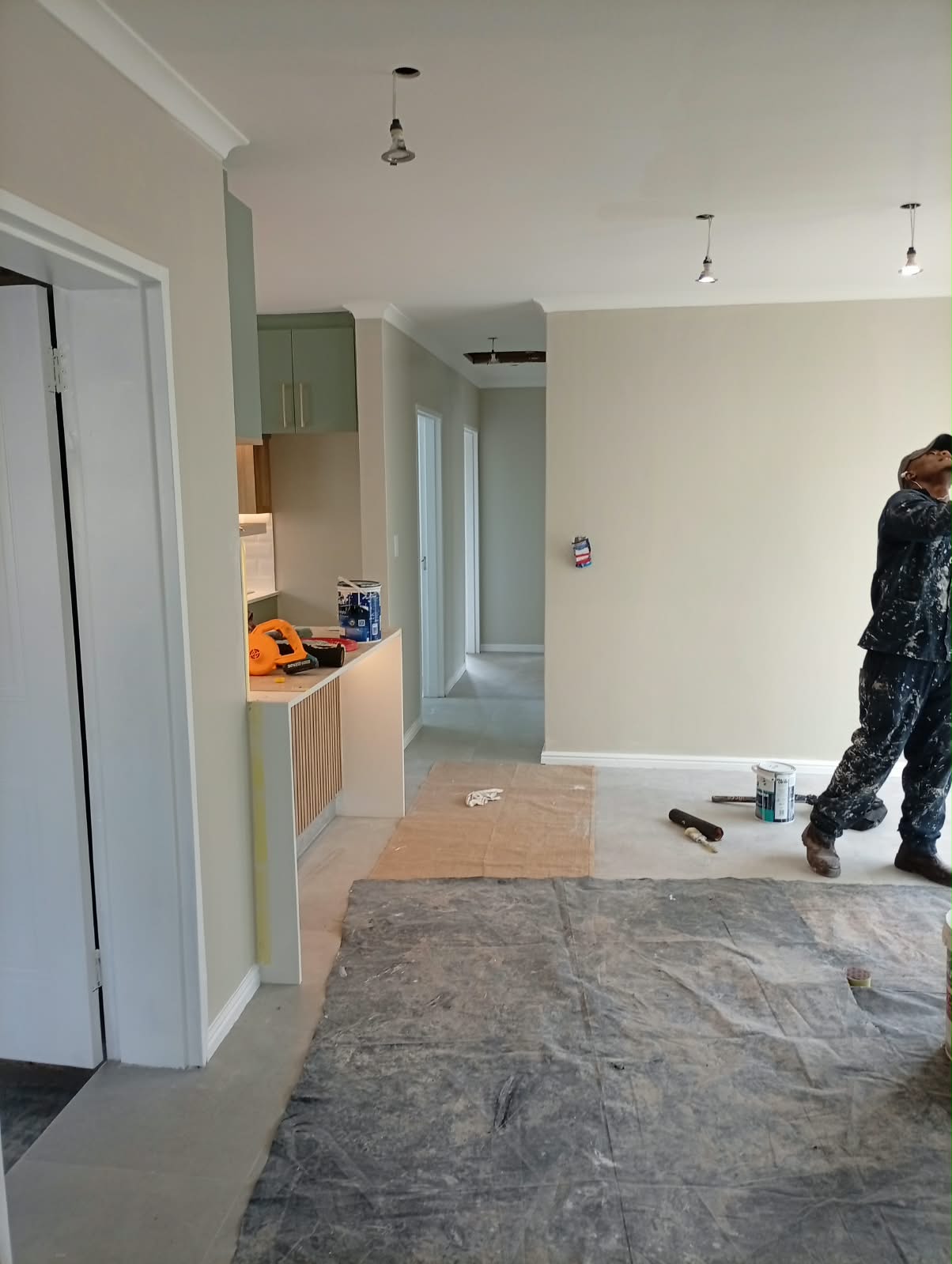 Painting an open-plan living area, protective sheeting down over the floor and furniture