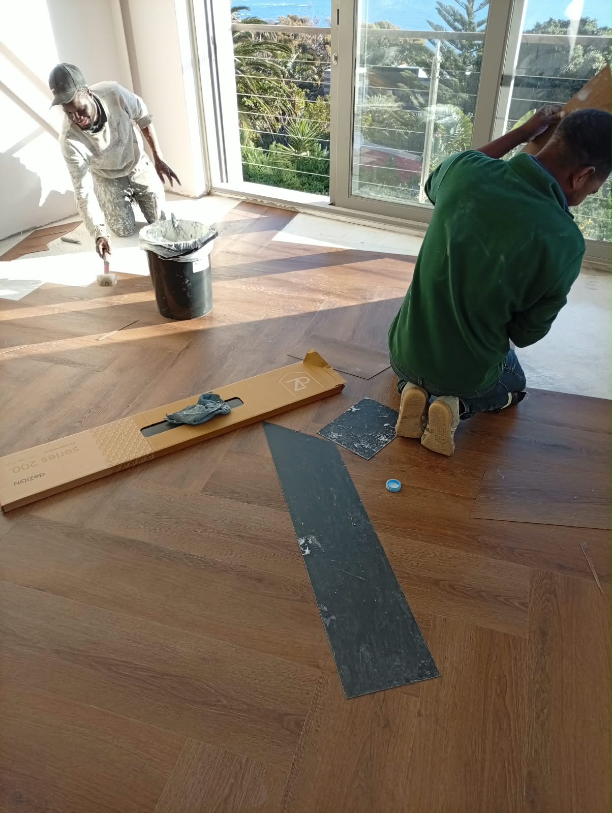 Grey floor tiles freshly laid in a corridor, with tile spacers still visible on the joints