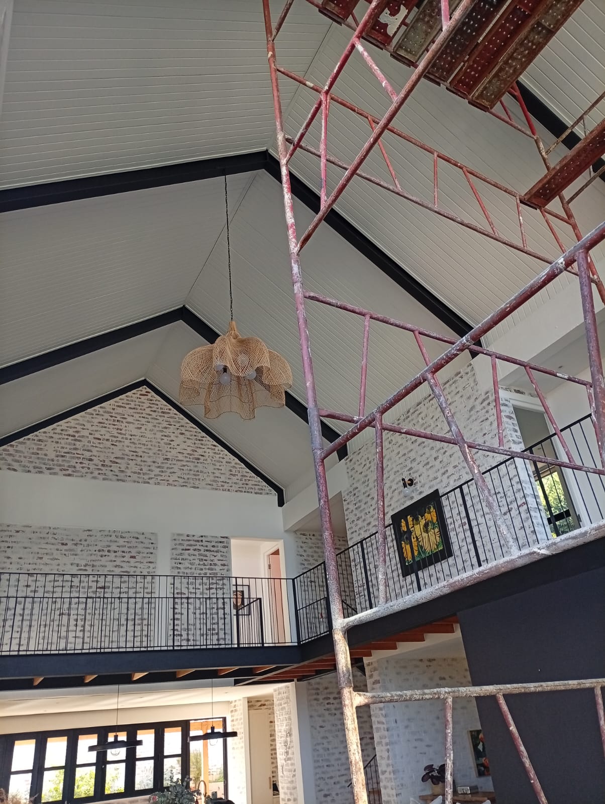 A finished double-volume renovation — white-washed brick feature walls, black steel beams and an open mezzanine over the kitchen and dining area